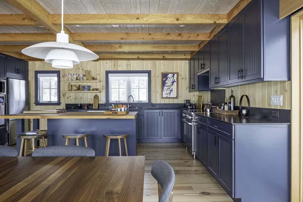 Kitchen with navy blue cabinetry, wood beams, and walnut dining table