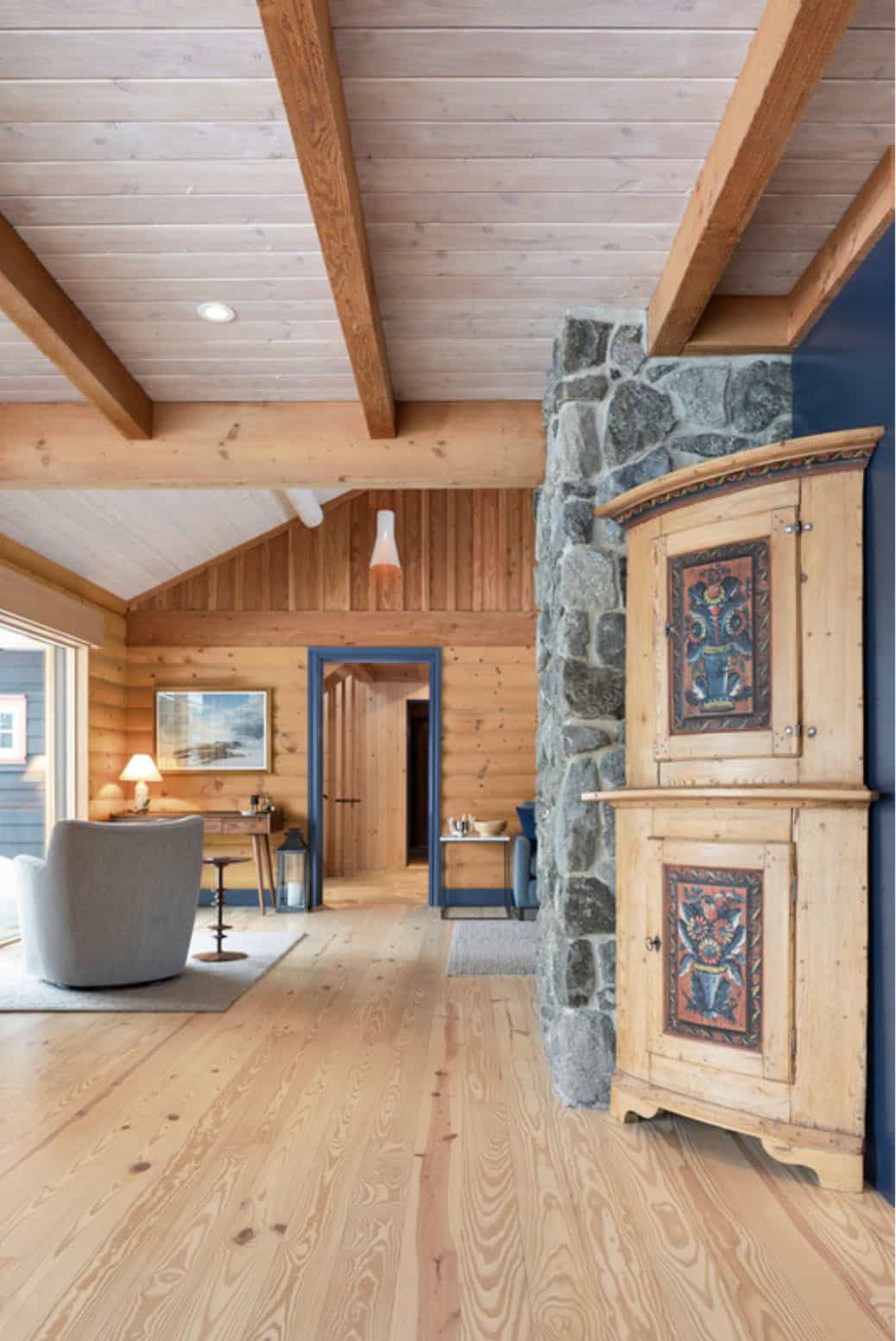 Living room corner with stone fireplace and painted Scandinavian cabinet