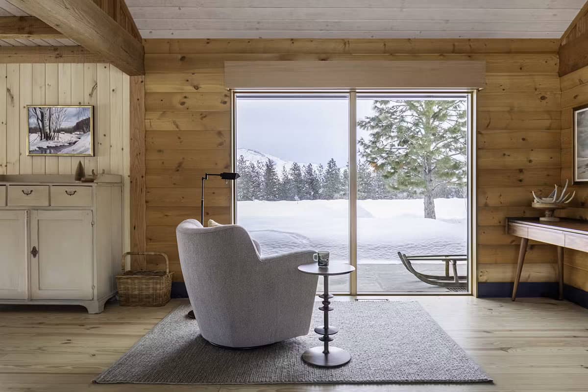 Reading nook with gray armchair facing large window and snowy view