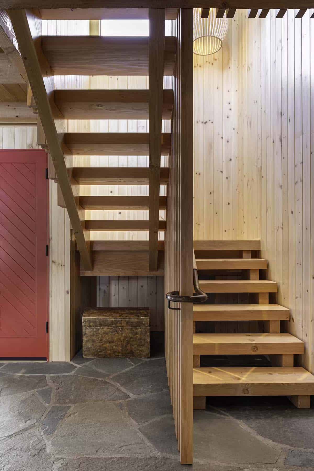 Wood staircase detail with red door and storage trunk below