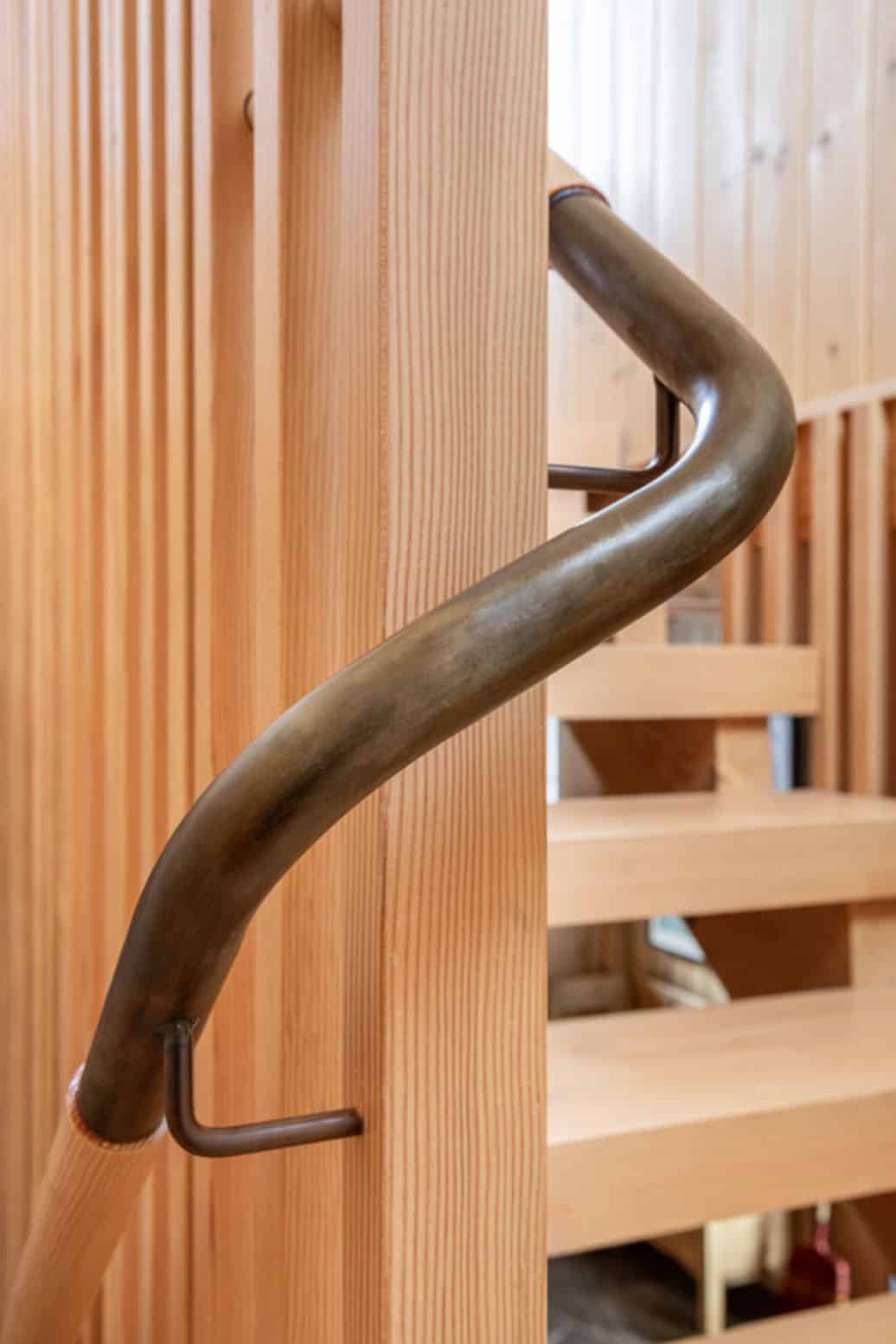 Close-up of bronze handrail against wood slat railing