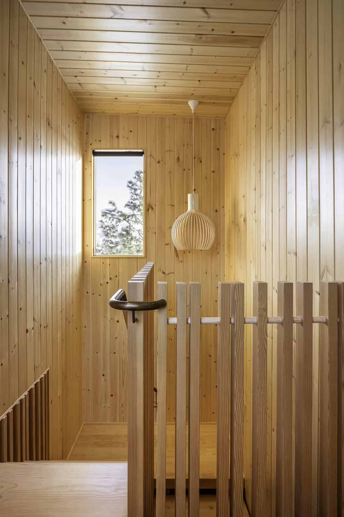 Wood-paneled stairway landing with pendant light and window