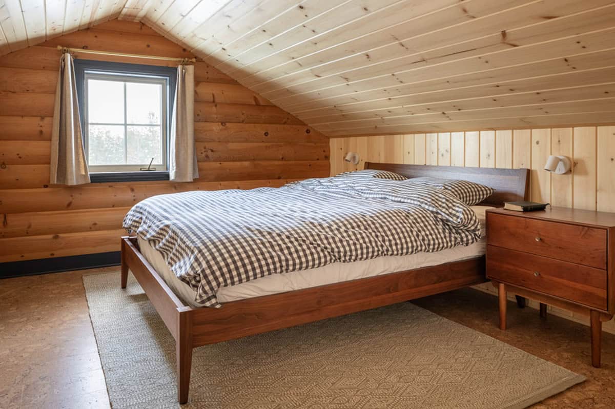 Attic bedroom with plaid bedding and wood-paneled sloped ceiling