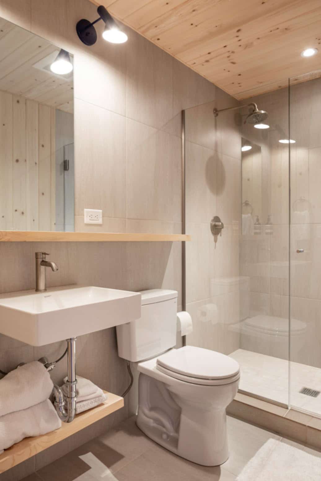 Modern bathroom with glass shower, floating vanity, and wood ceiling