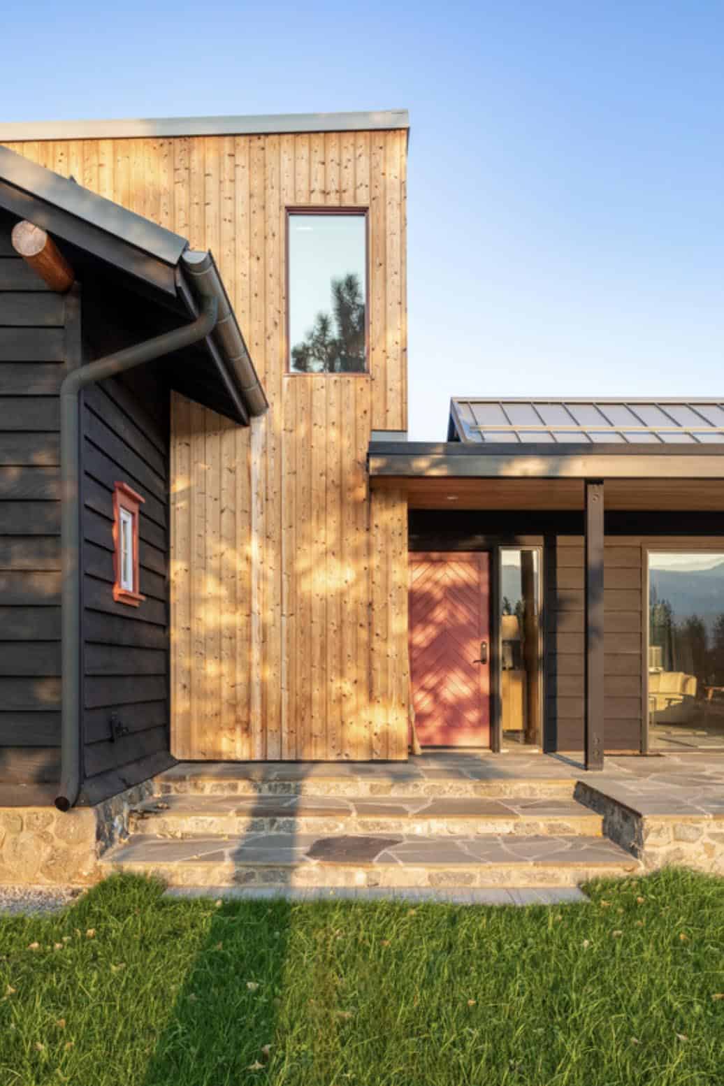 Close-up of wood-clad addition with red front door and stone entry steps