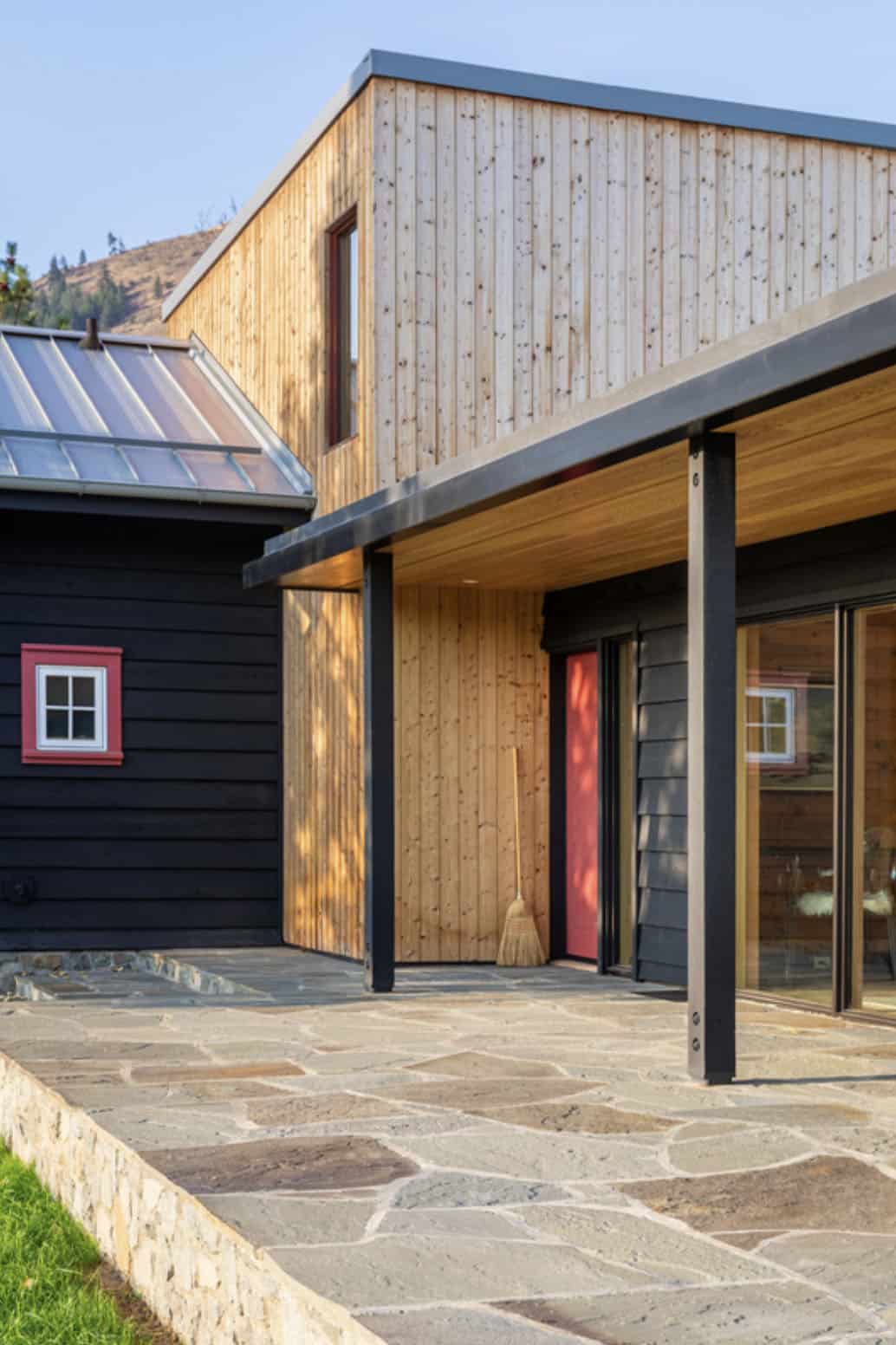 Corner detail of black cabin with wood addition and covered patio