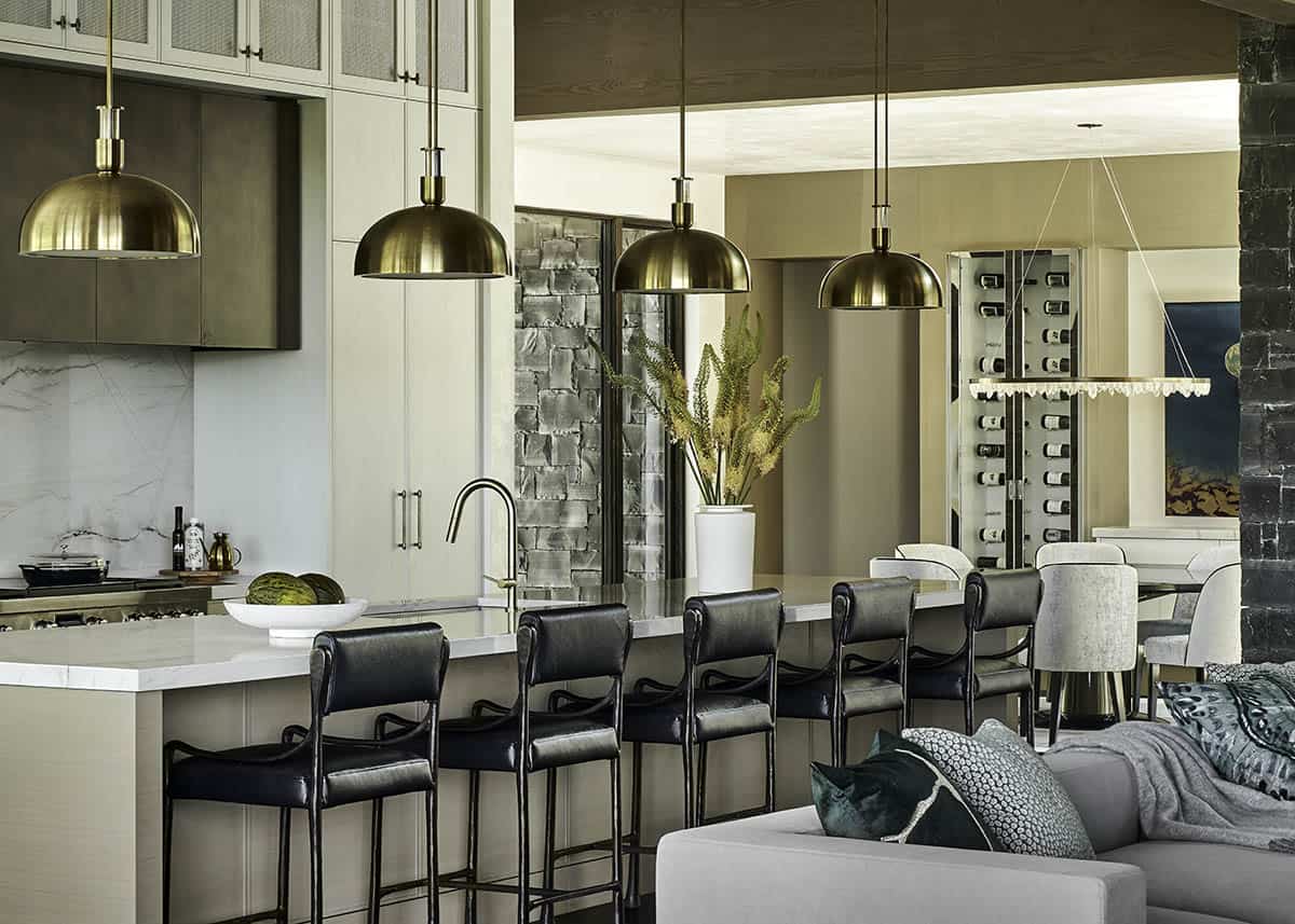Kitchen island with brass dome pendant lights and black leather bar stools