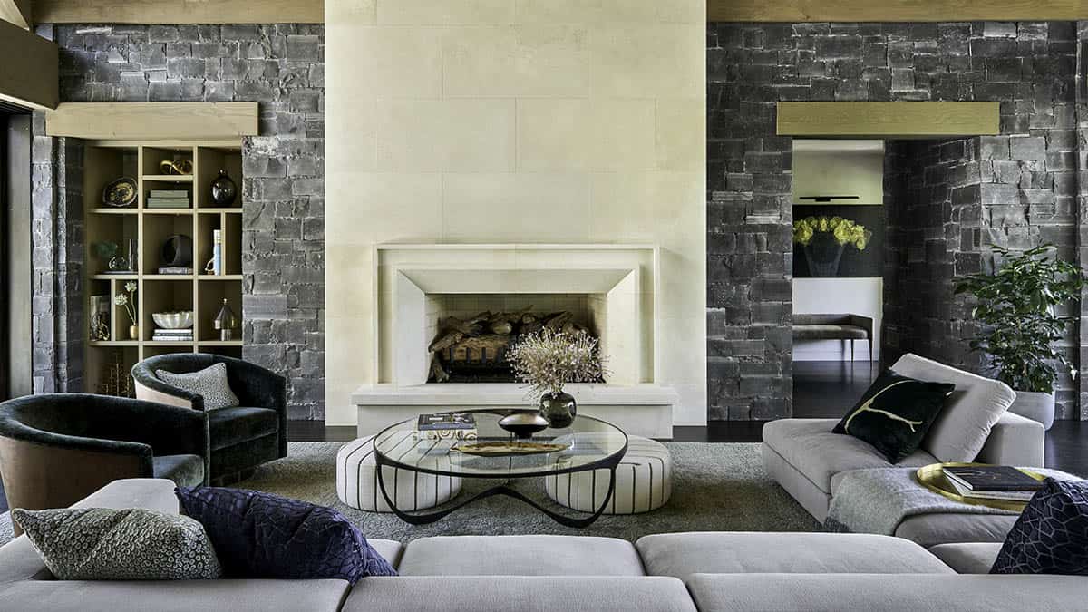 Living room with stone fireplace, dark stacked-stone walls, and gray sectional sofa