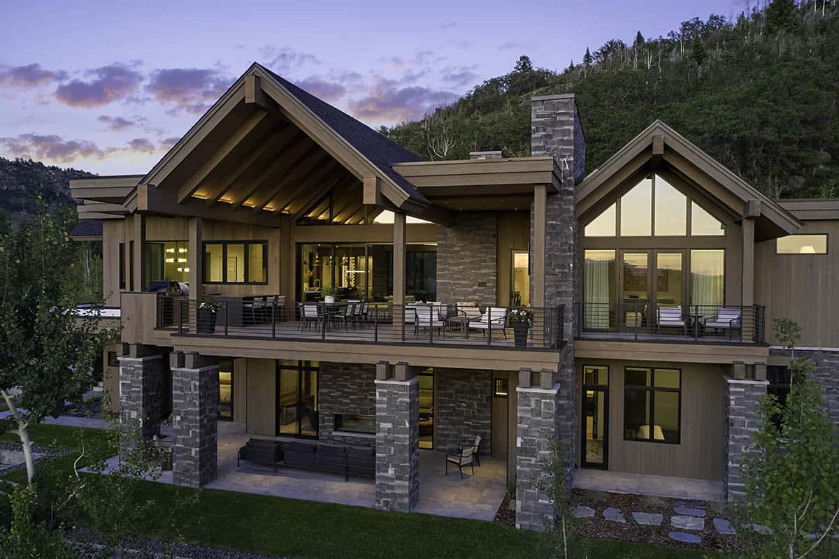 Exterior of mountain home at dusk with covered deck and stone columns