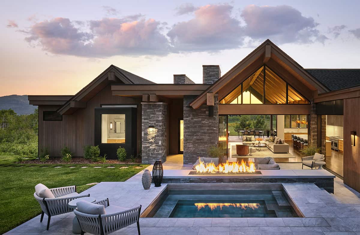 Backyard patio with pool, fire feature, and open-concept living space visible through glass doors