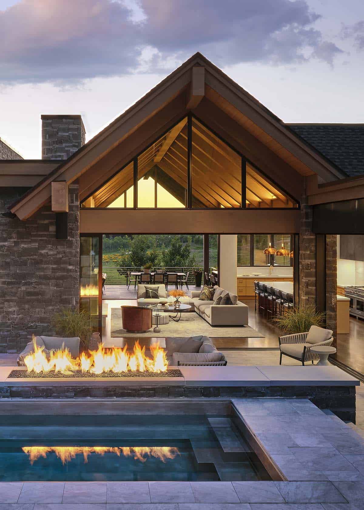 Vertical view of covered patio, pool, and fire pit beneath a peaked timber roof