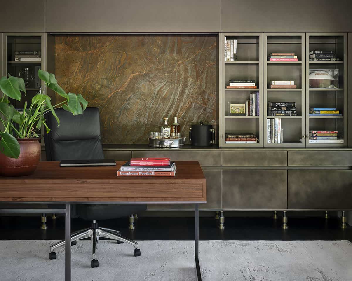Home office with leather desk chair, wood desk, and marble-backed built-in shelving