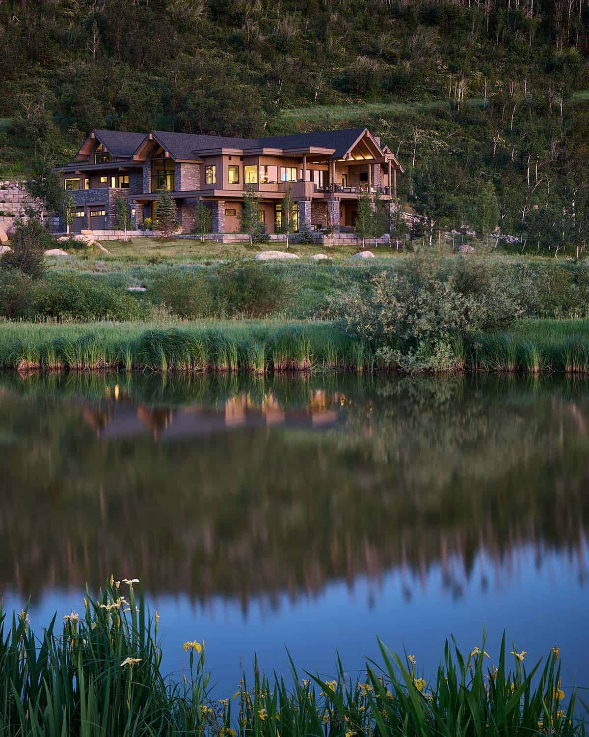 Vertical dusk shot of mountain retreat with pond reflection in foreground