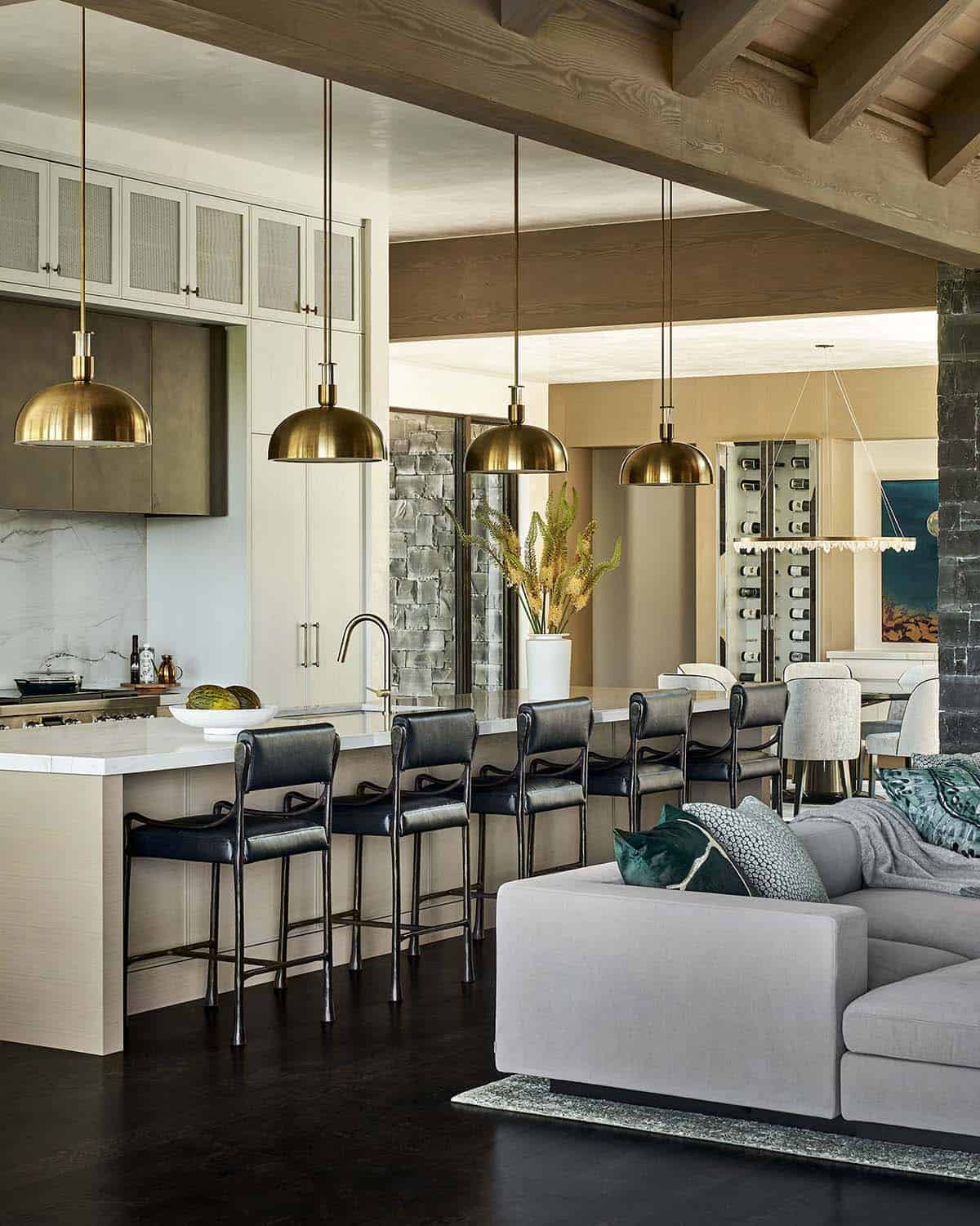 Kitchen and living space under wood-beam ceiling with brass pendant lights