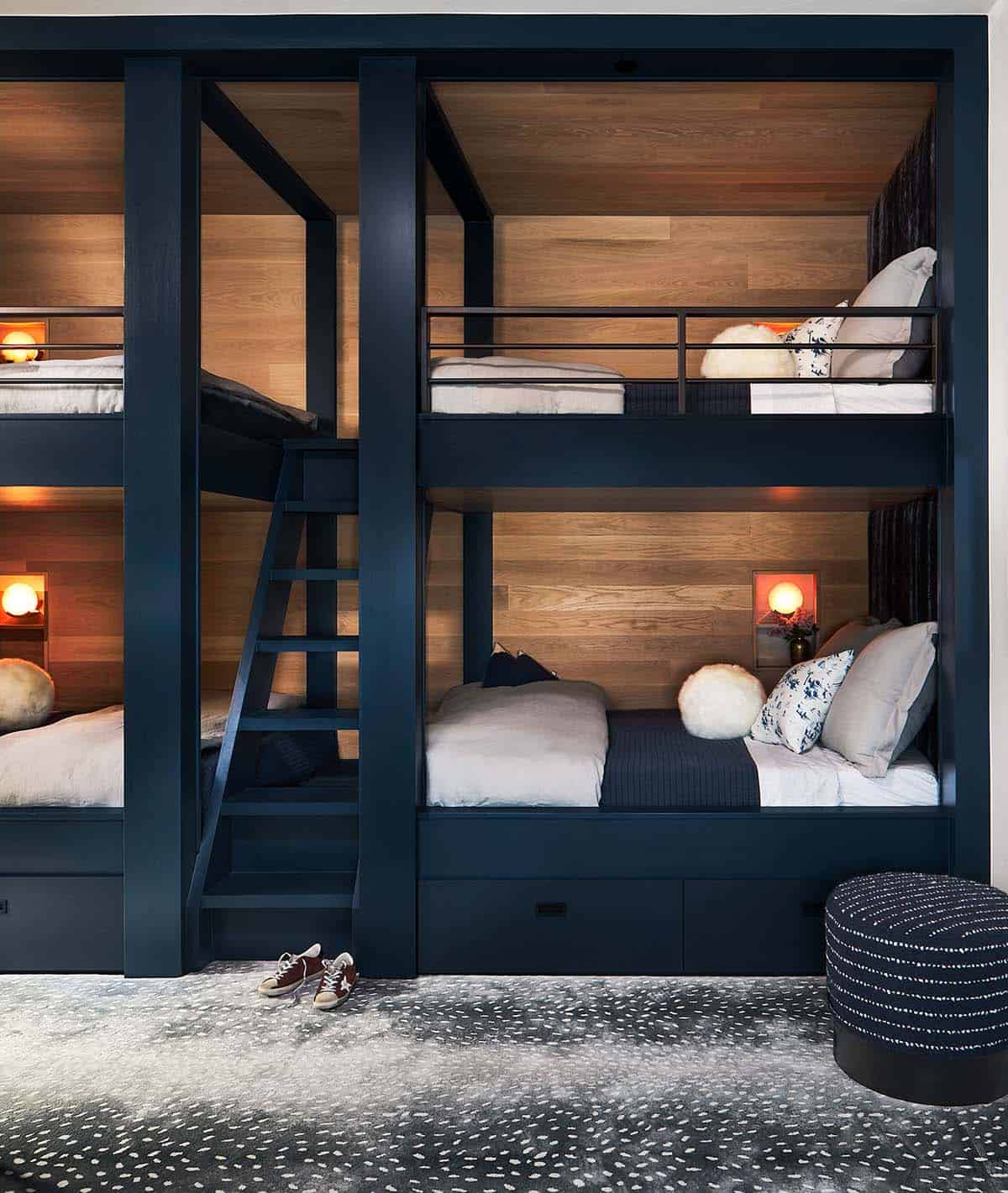 Built-in navy bunk beds with wood paneling and ladder in a kids' room