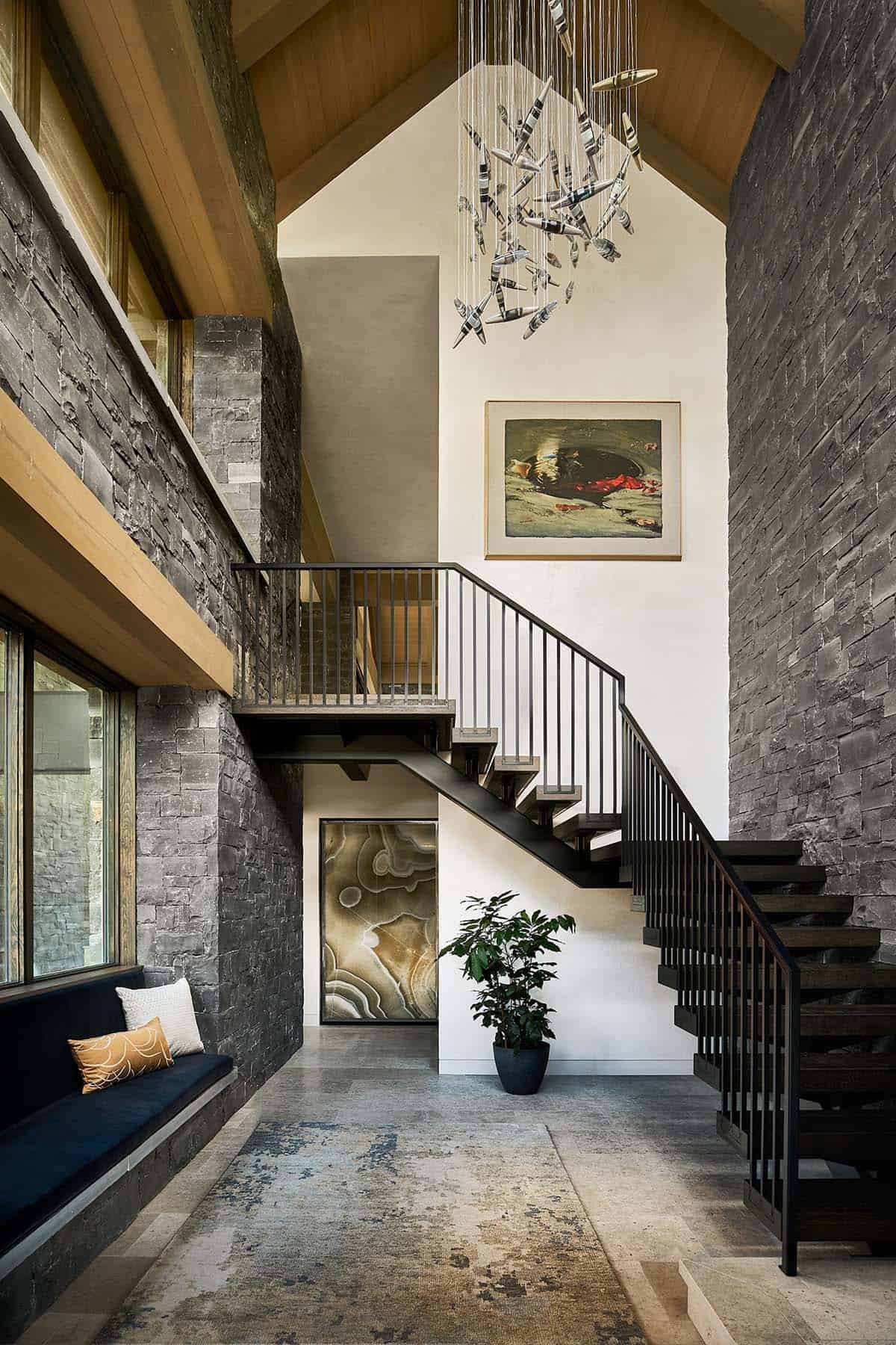 Vertical view of staircase with sculptural pendant light and stone accent walls