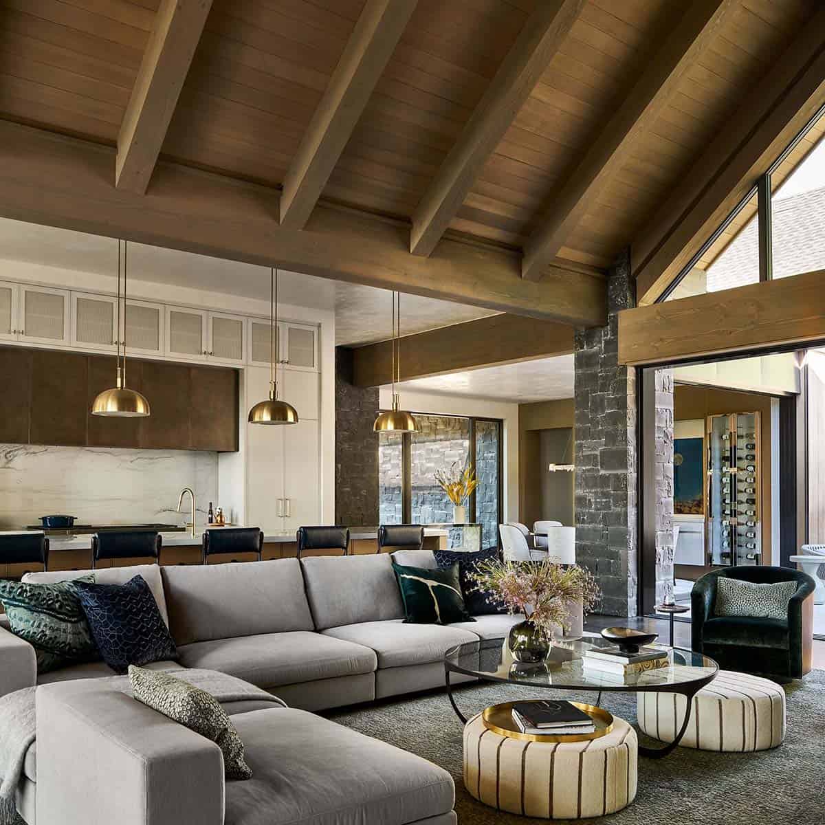 Wide view of living, kitchen, and dining areas beneath vaulted wood ceiling