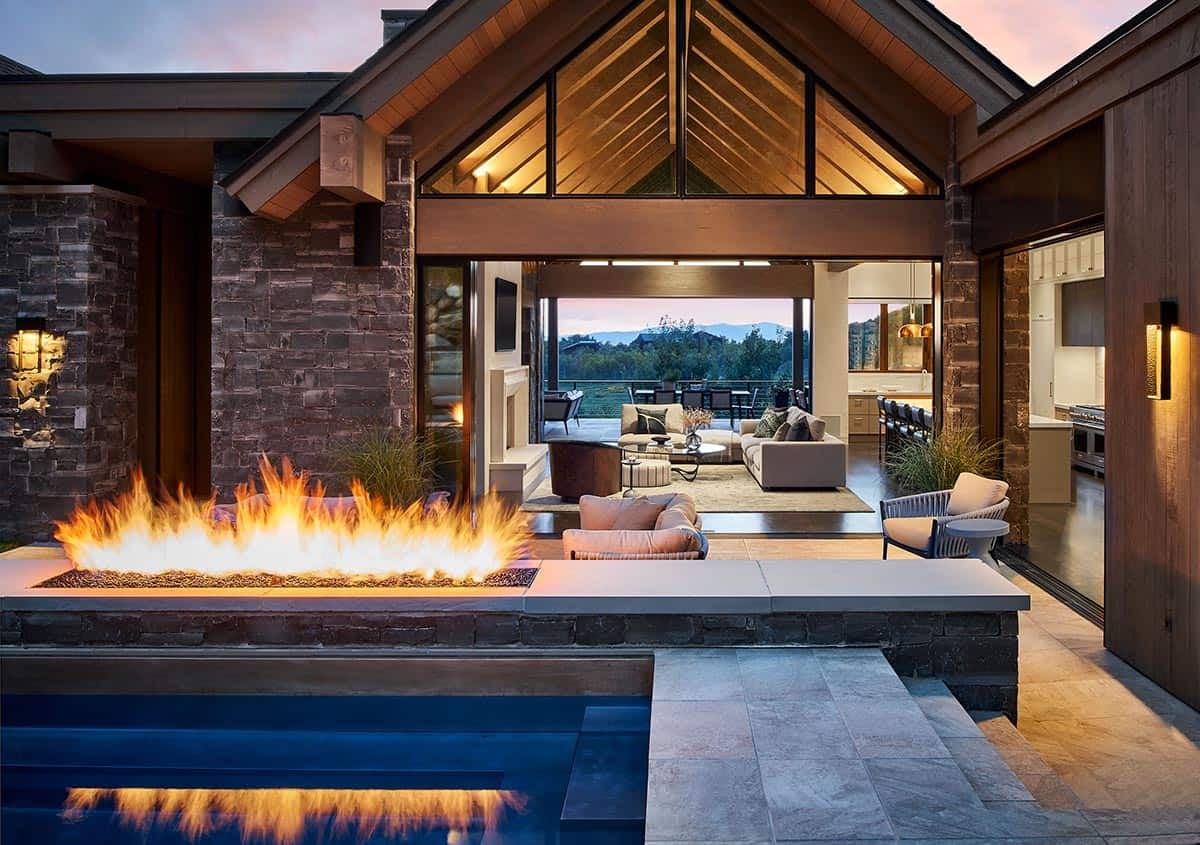 Covered outdoor patio and pool with fire feature overlooking mountain view at dusk