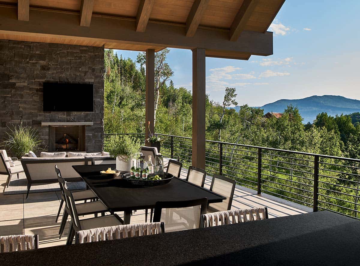 Outdoor dining and lounge area with stone fireplace and mountain view