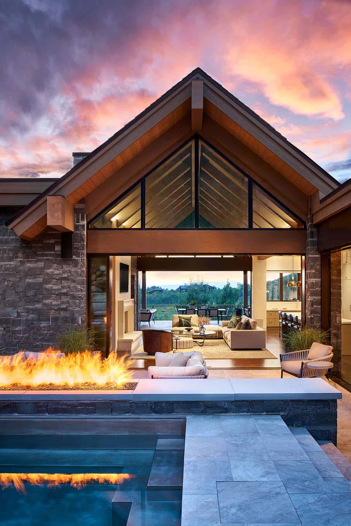Vertical dusk view of gabled roofline framing pool, patio, and living space
