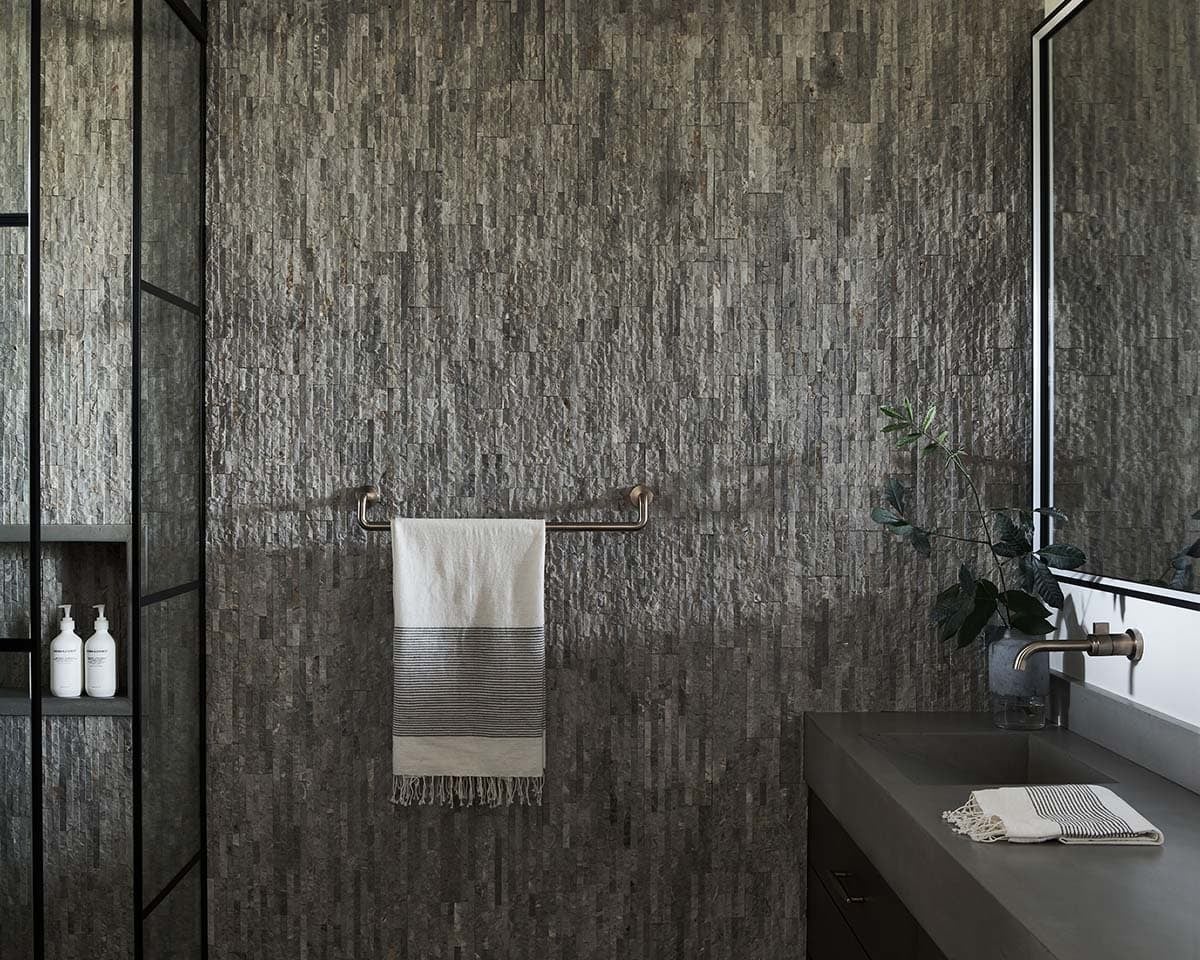 Bathroom with textured stone accent wall, towel bar, and vanity sink