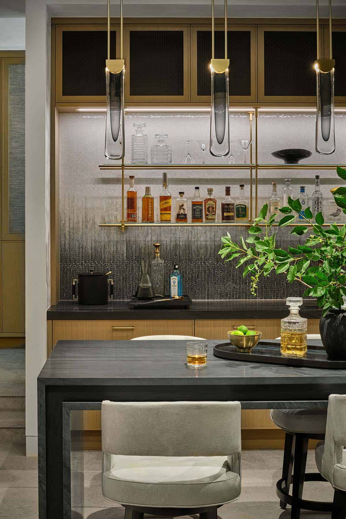 Wet bar with hanging glass pendant lights, shelved liquor bottles, and dining table