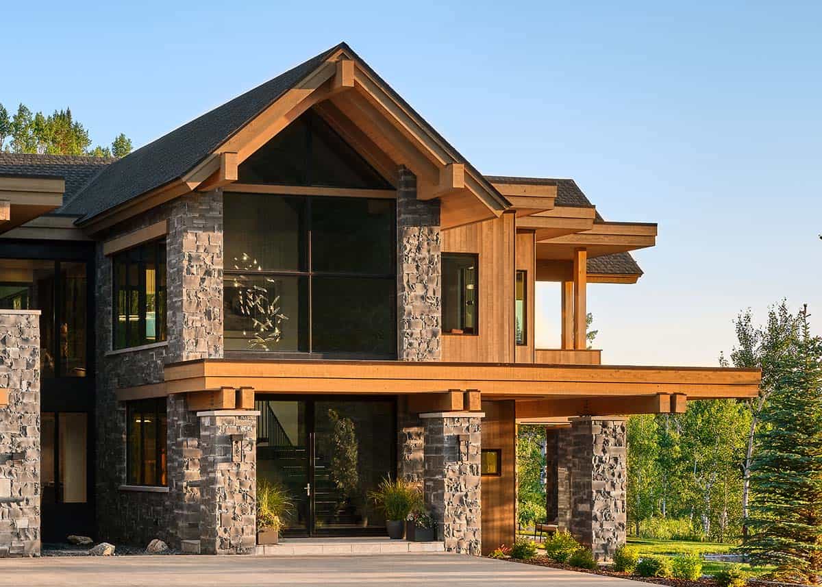 Close-up of home's stone-and-timber entrance with gabled roof and glass door