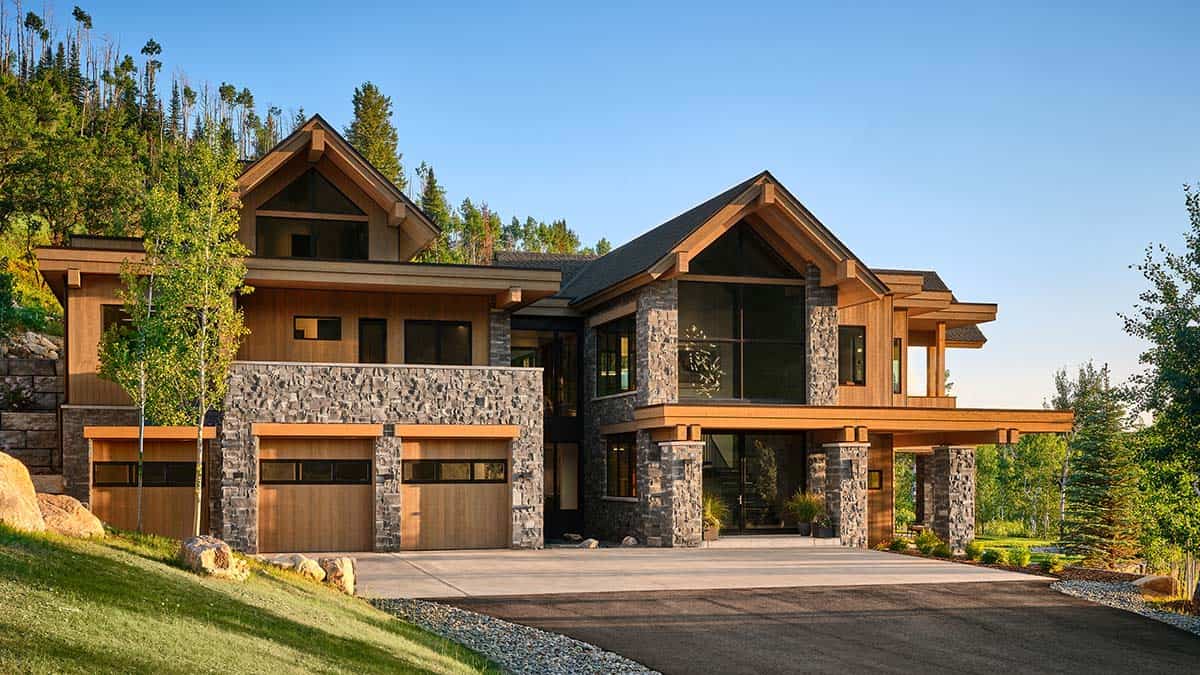 Front exterior of mountain home with stone accents, wood siding, and three-car garage