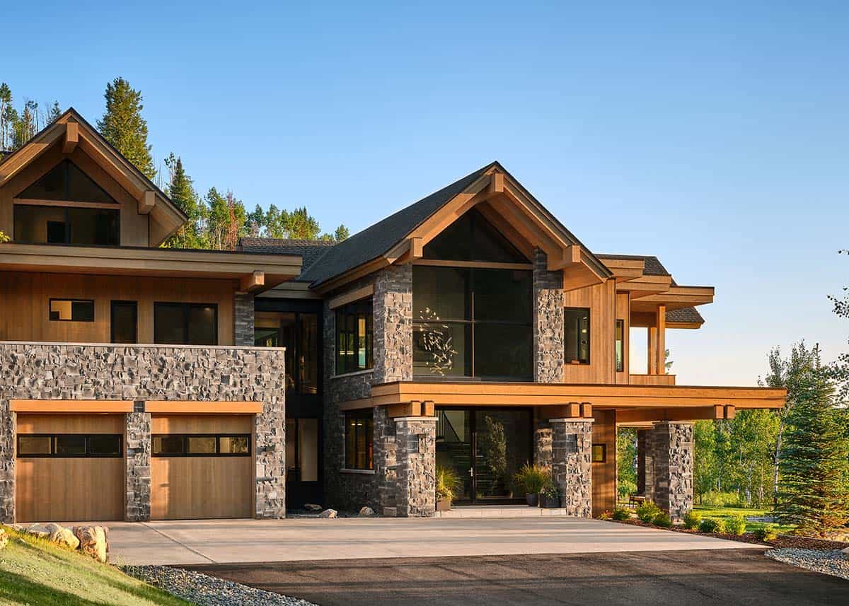 Front view of home's entrance with stone pillars, timber beams, and garage
