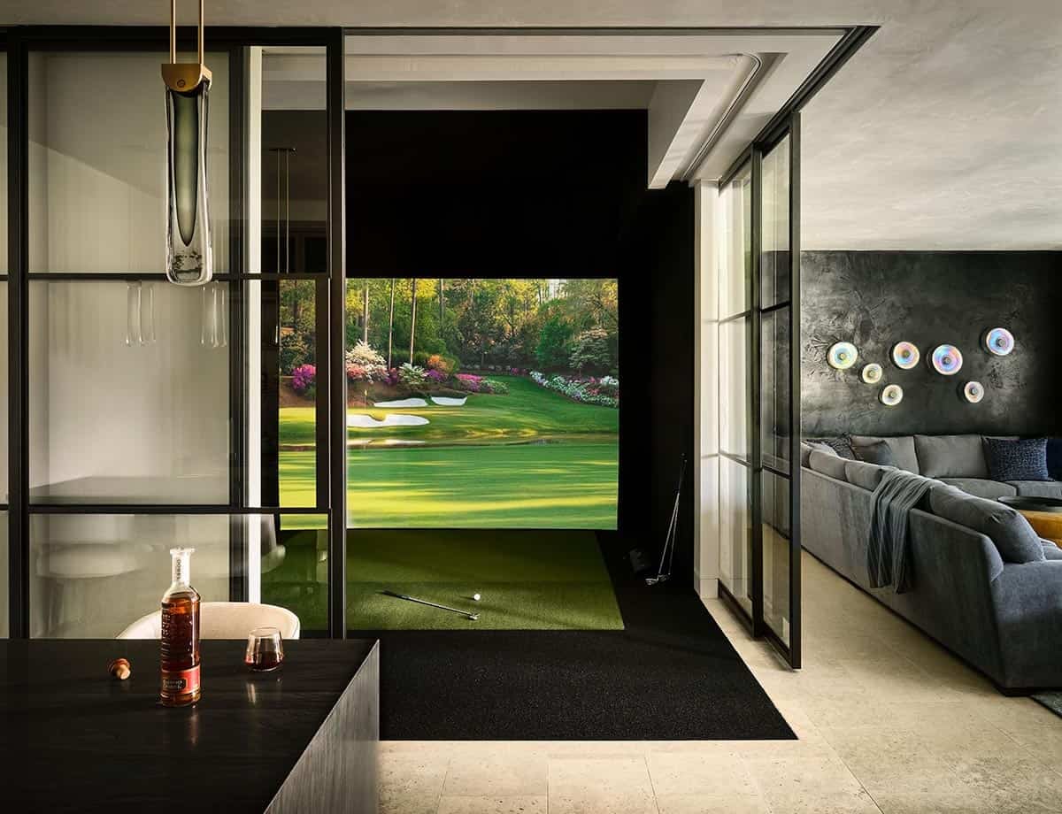 Indoor golf simulator with turf, clubs, and screen showing a green fairway