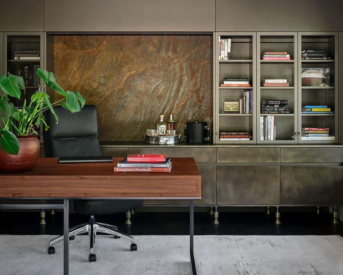 Home office desk with leather chair, marble-backed shelving, and potted plant
