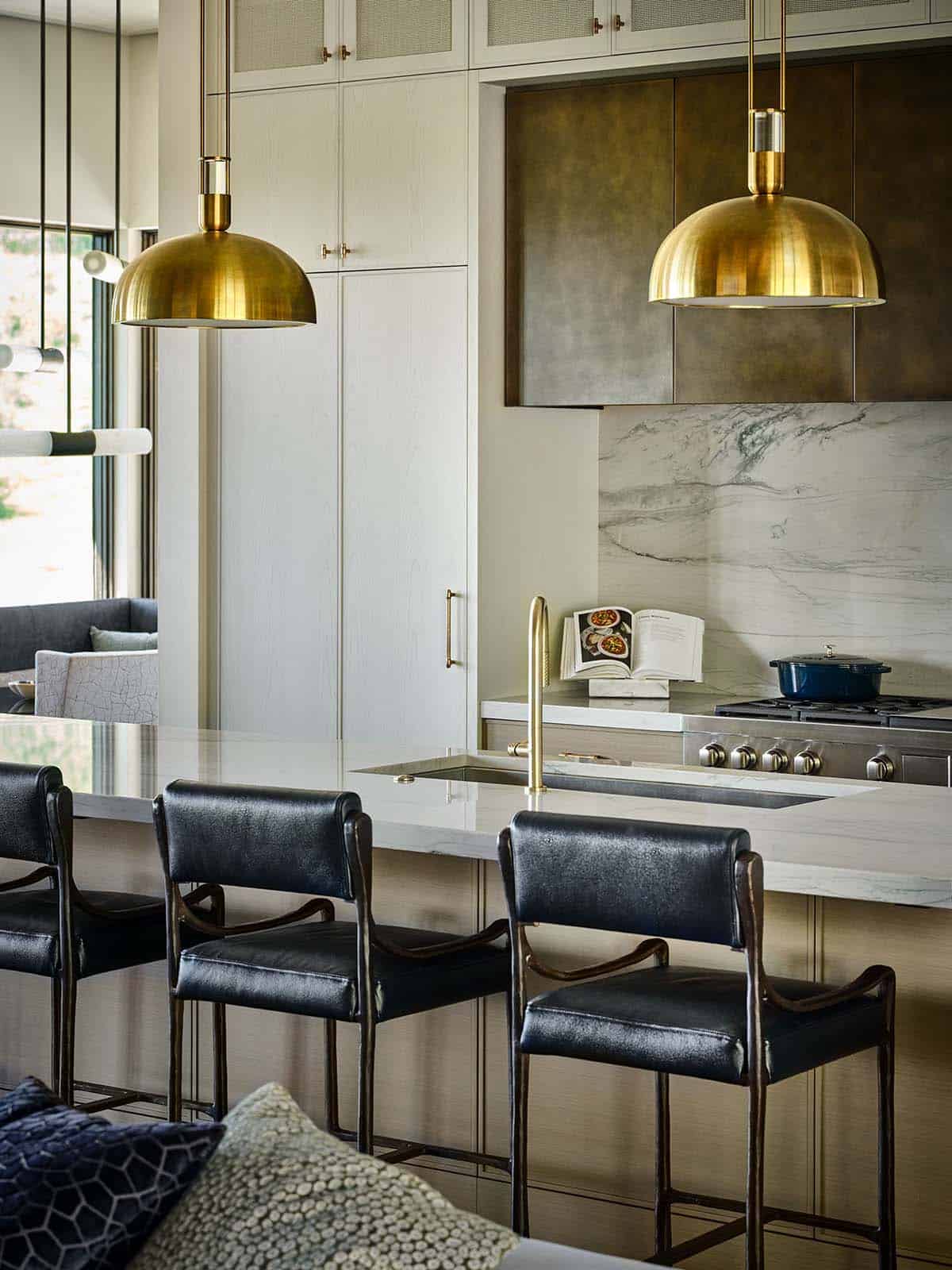 Kitchen stove area with brass pendant lights and marble backsplash