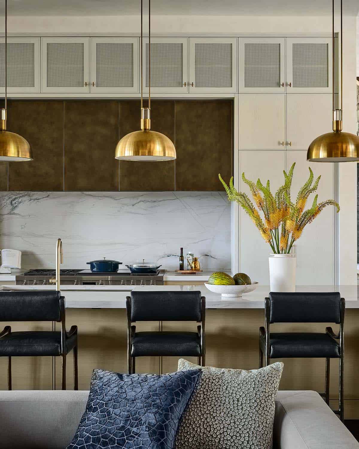 Kitchen counter with brass pendants, bronze cabinetry, and vase of yellow flowers