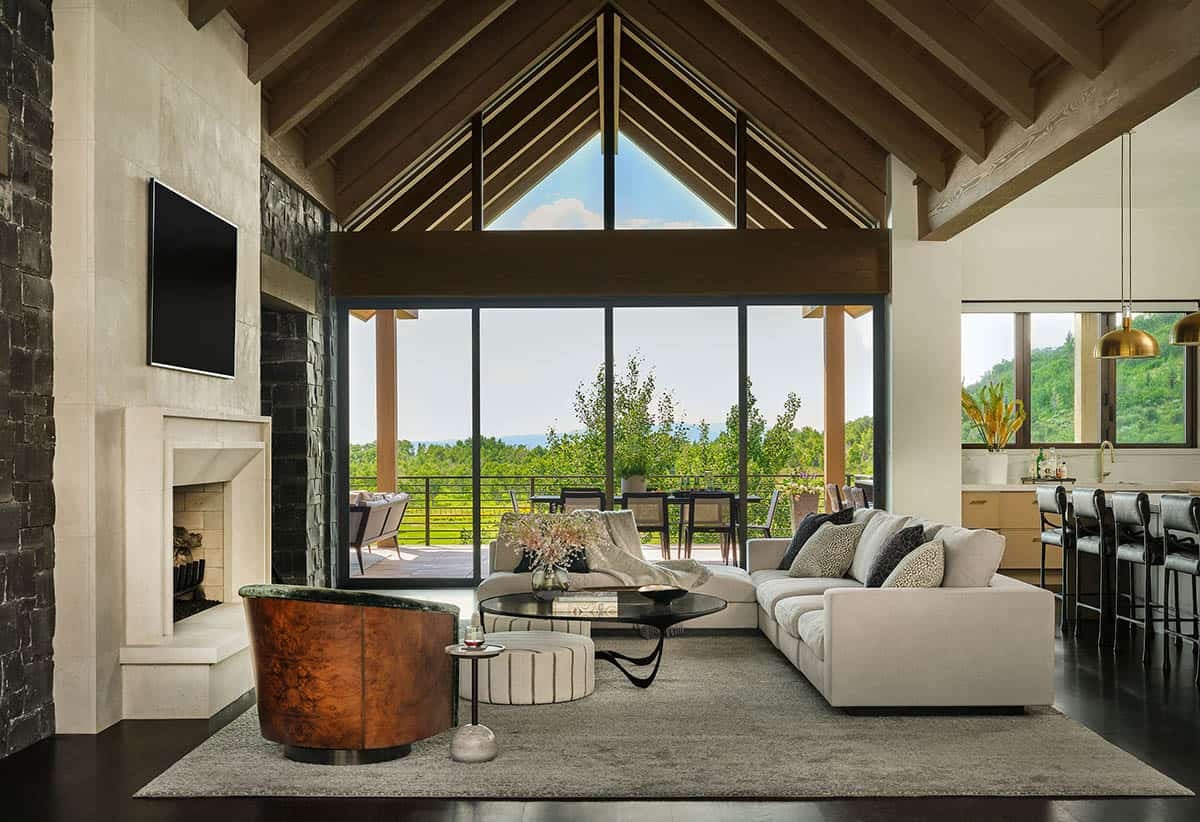 Living room with vaulted ceiling, sectional sofa, and glass wall opening to patio
