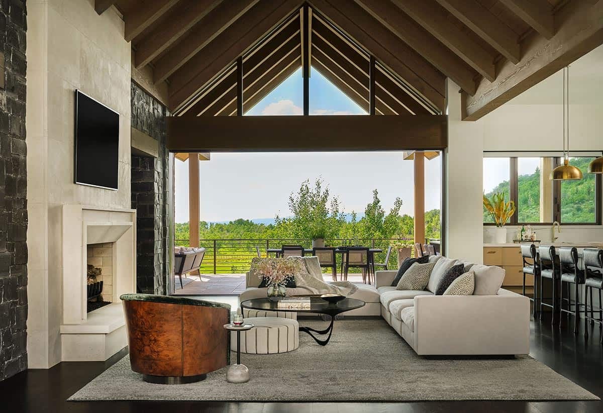 Wide living room view with wood-beam ceiling, sofa, and kitchen beyond