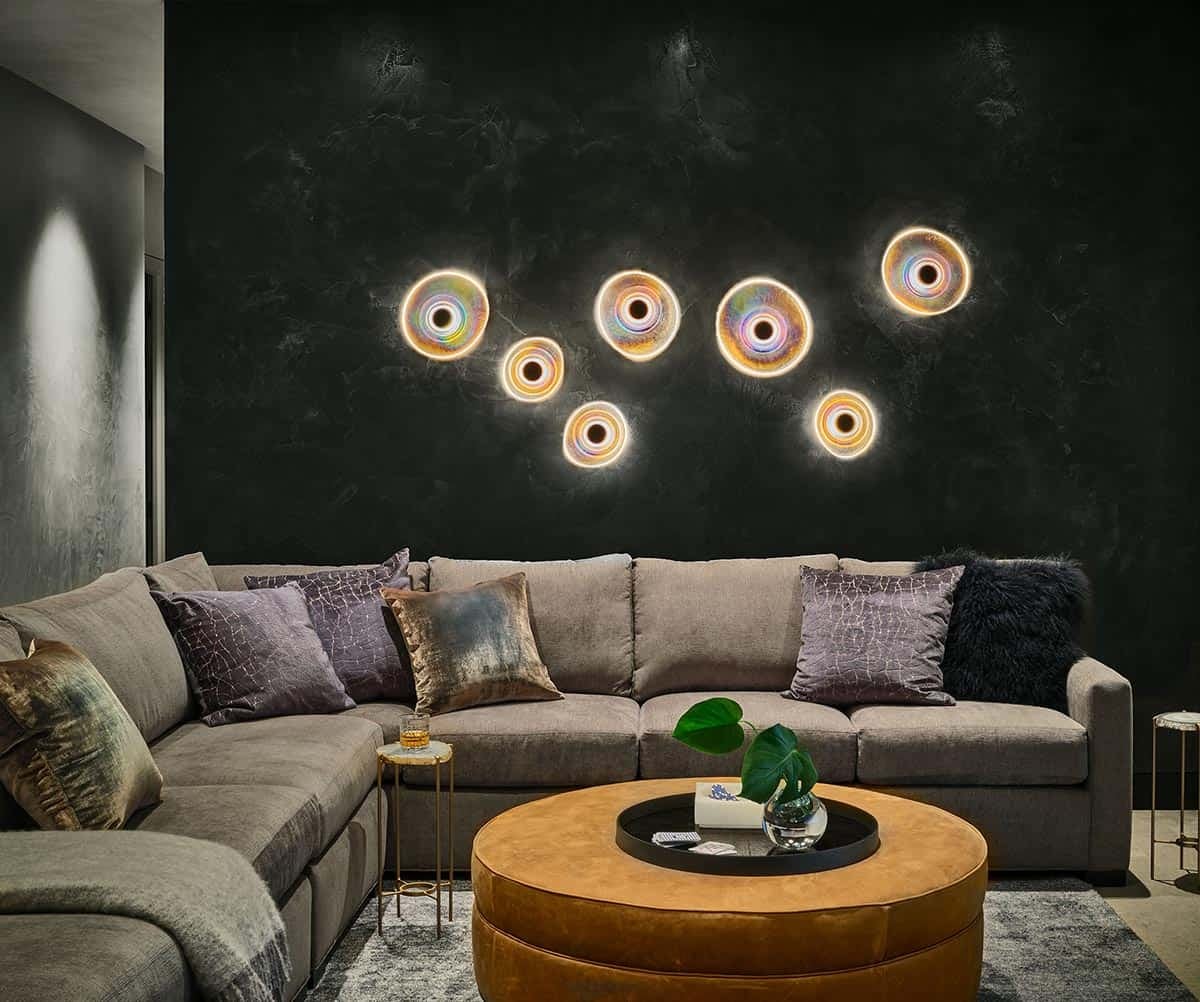 Sectional sofa beneath dark accent wall with iridescent circular sconces