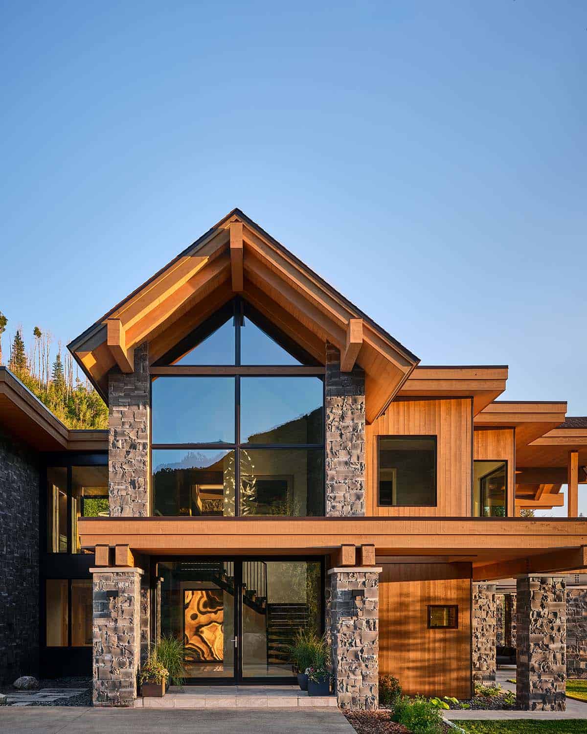 Front exterior of mountain home with peaked timber gable and stone pillars