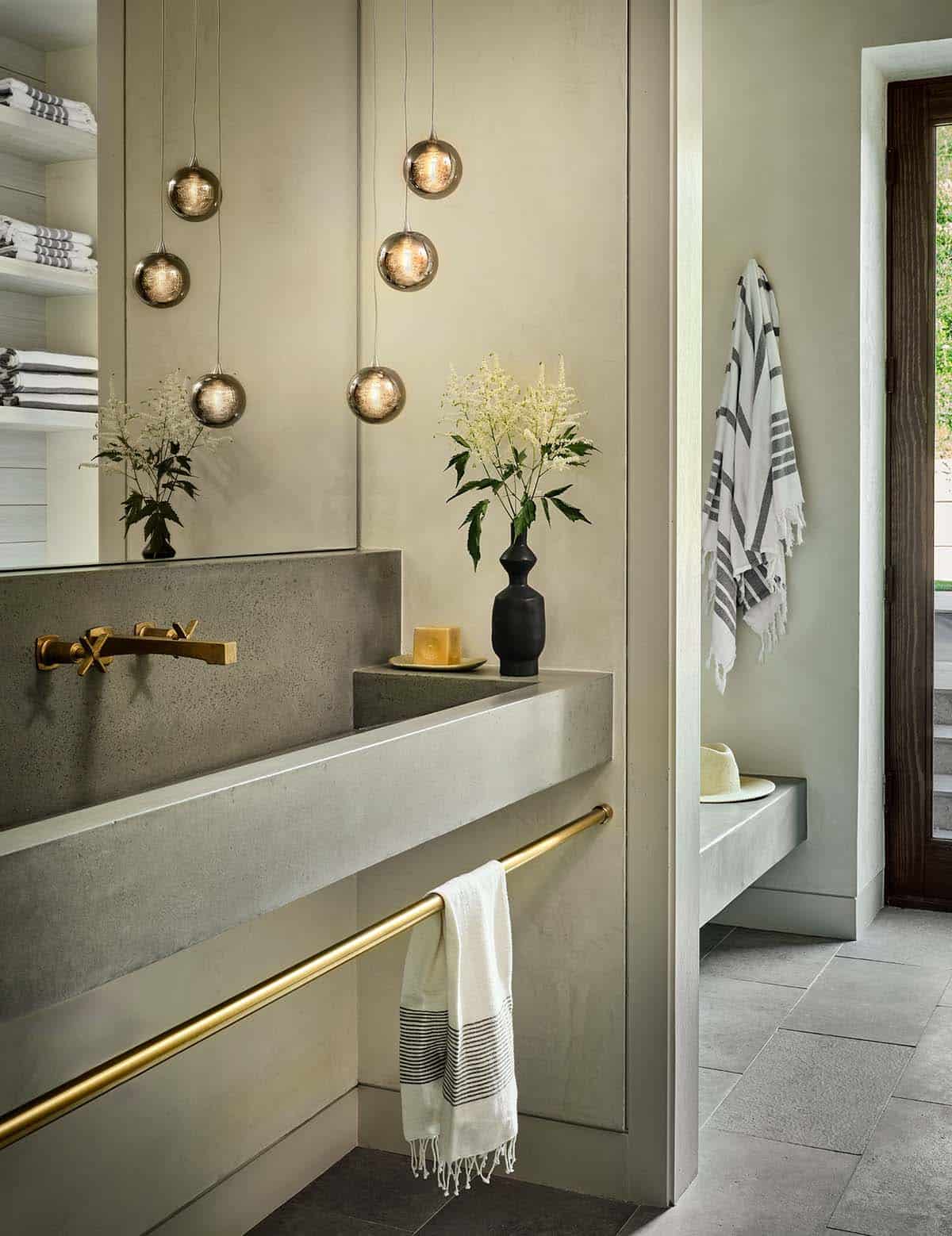 Mudroom sink with round pendant lights, brass fixtures, and striped towels