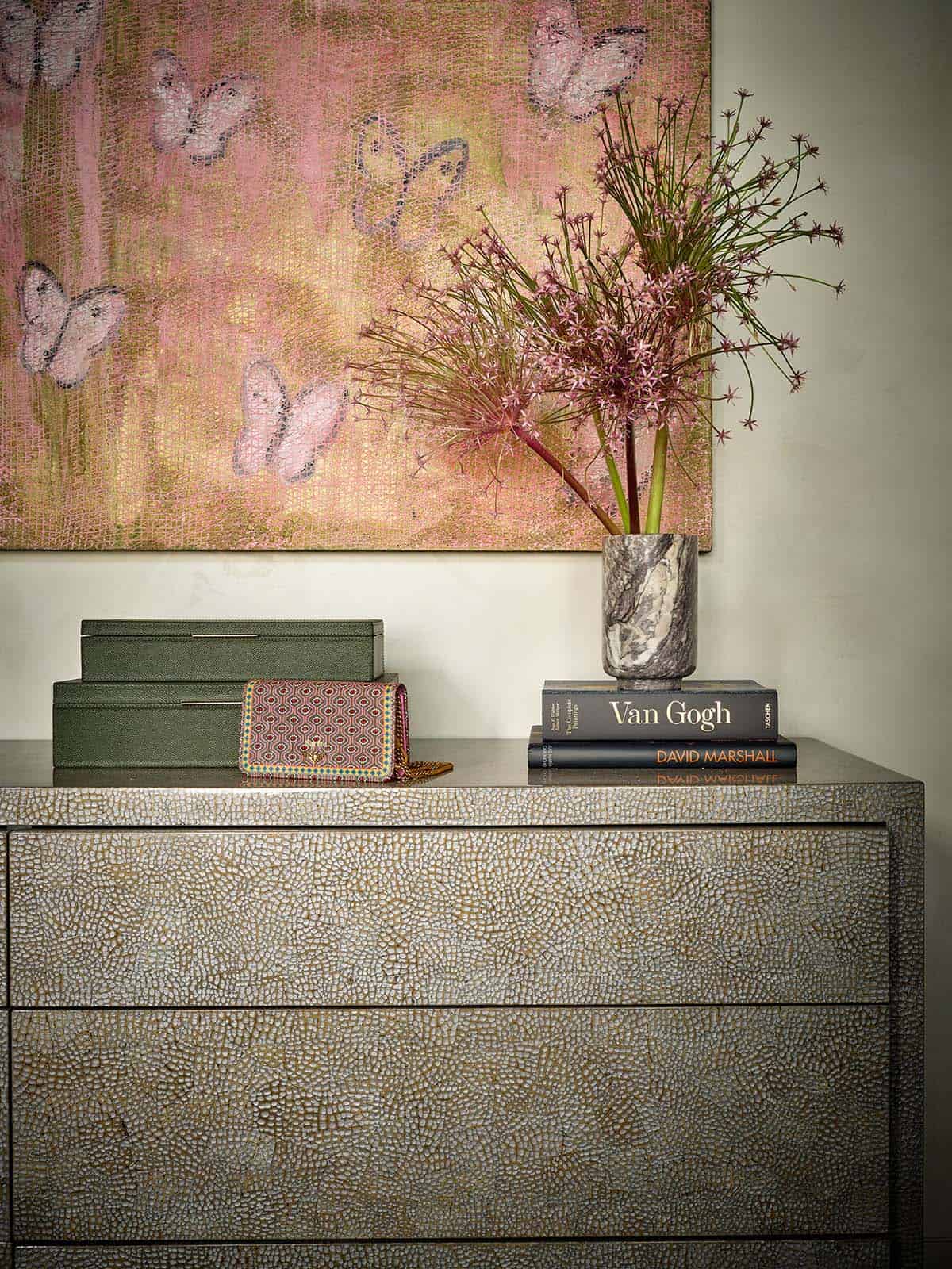 Dresser vignette with decorative boxes, marble vase, and butterfly artwork