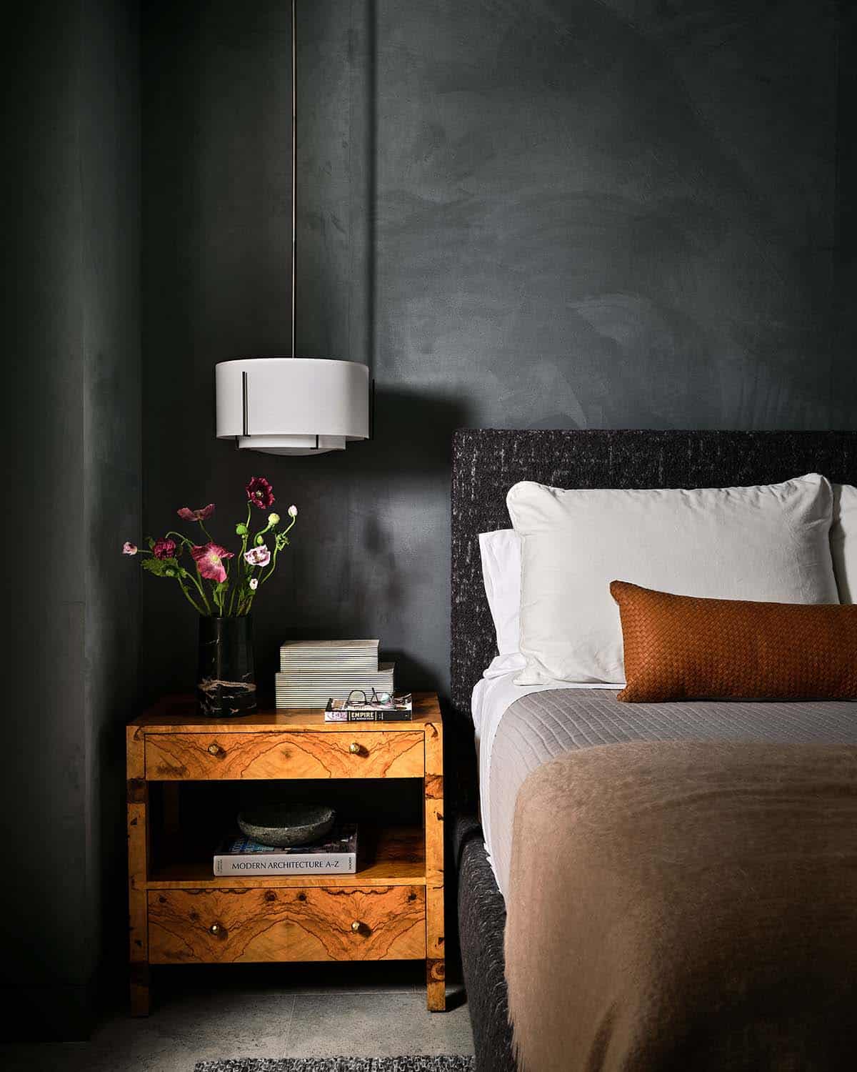 Dark moody bedroom nook with burl wood nightstand and drum pendant light