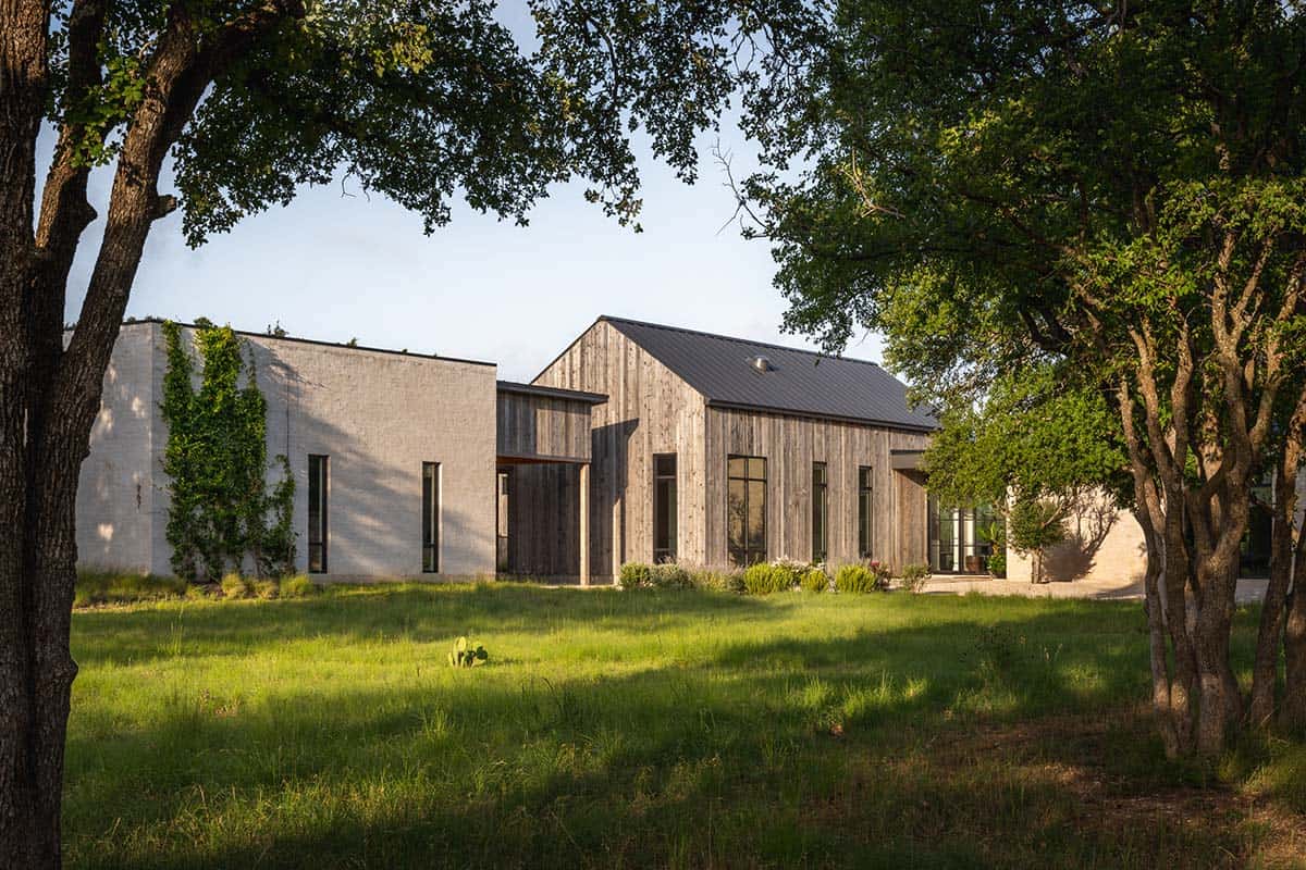Mid-century prairie home exterior framed by mature oak trees at dusk