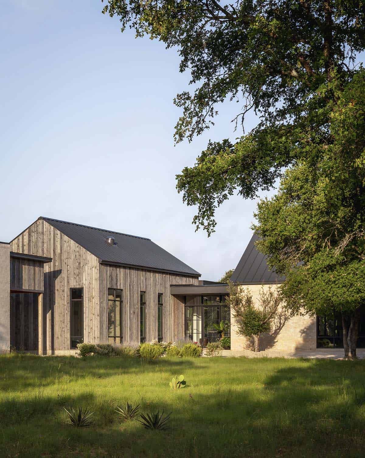 Wood-clad gable and limestone volumes connect beneath a dark standing-seam roof