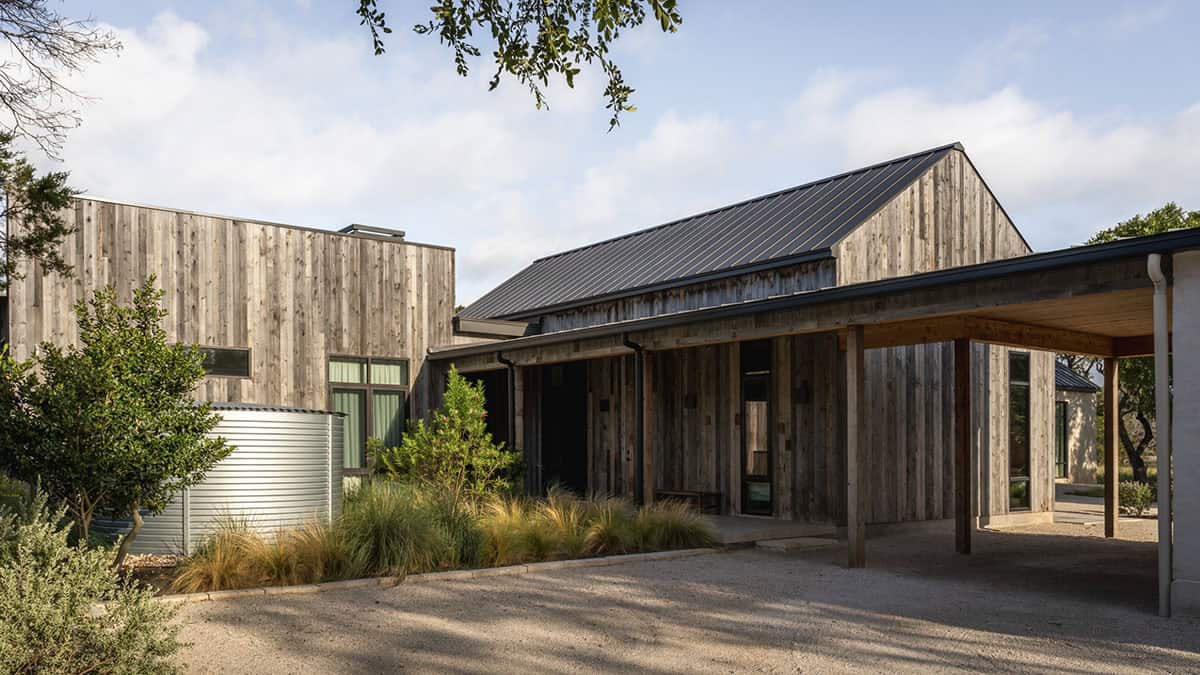 Rainwater collection tank sits beside the home's timber-clad side entrance