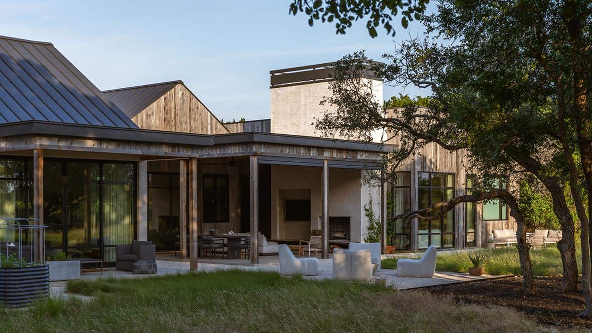 Rear patio with white lounge chairs faces the wood and stucco facade