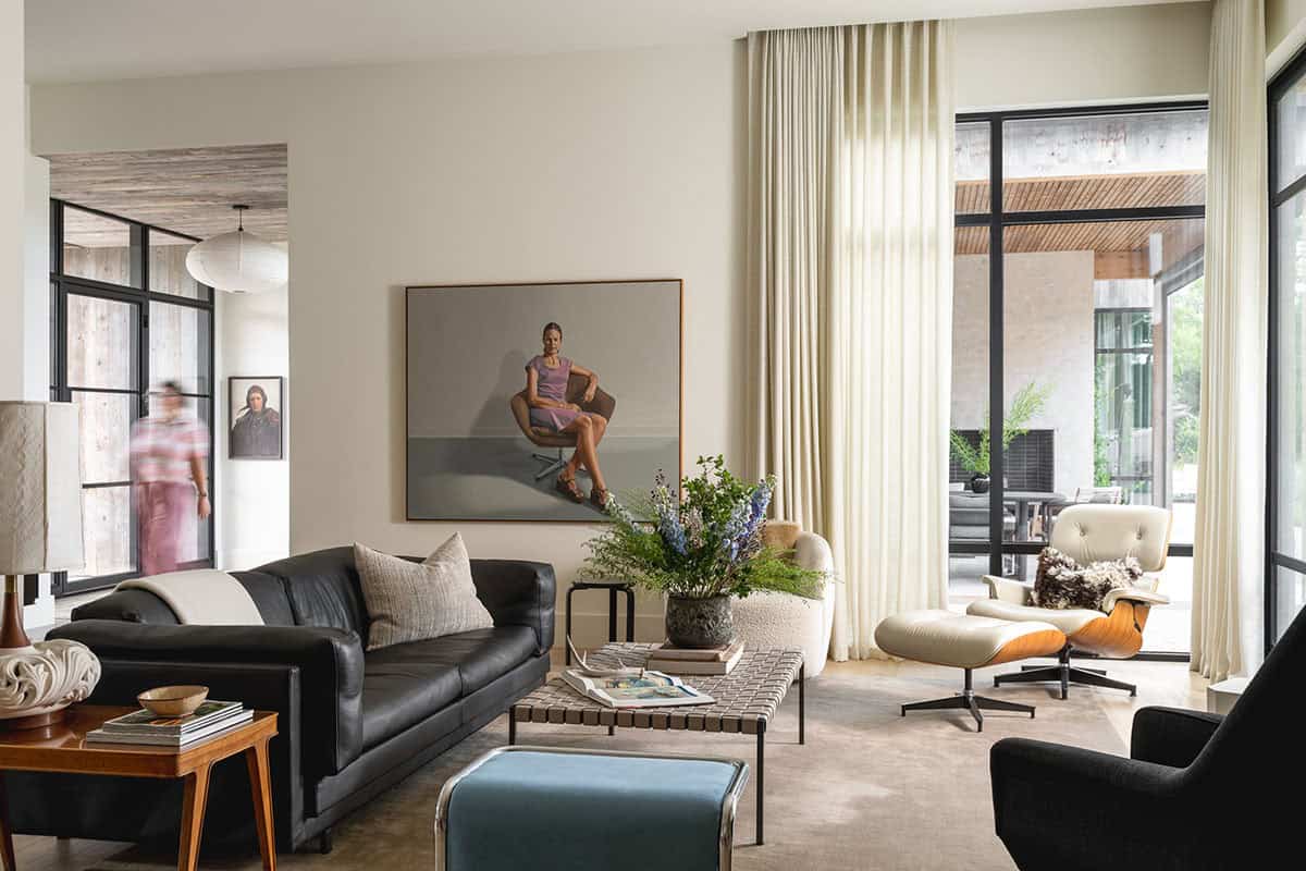 Living room with black leather sofa and tan curtains beside glass doors