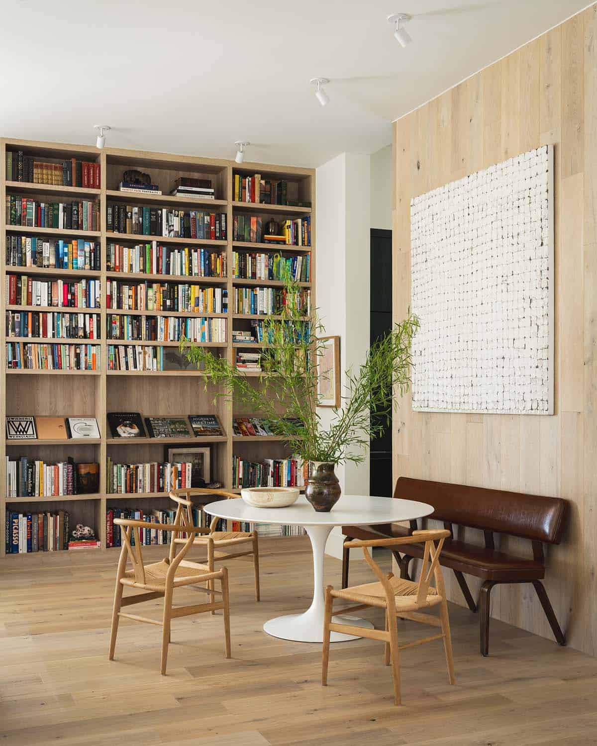 Built-in library shelving surrounds a round dining table and wishbone chairs