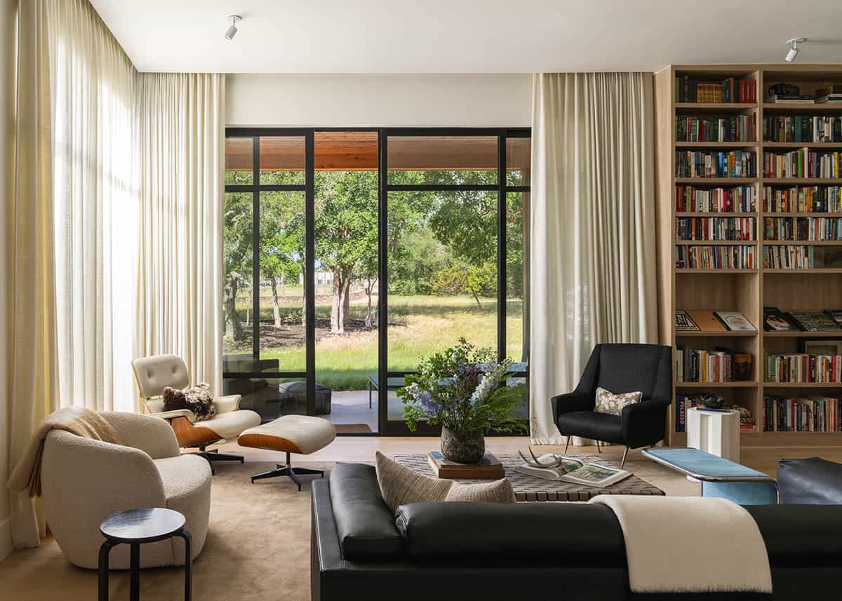 Living room seating area framed by floor-to-ceiling curtains and bookshelves