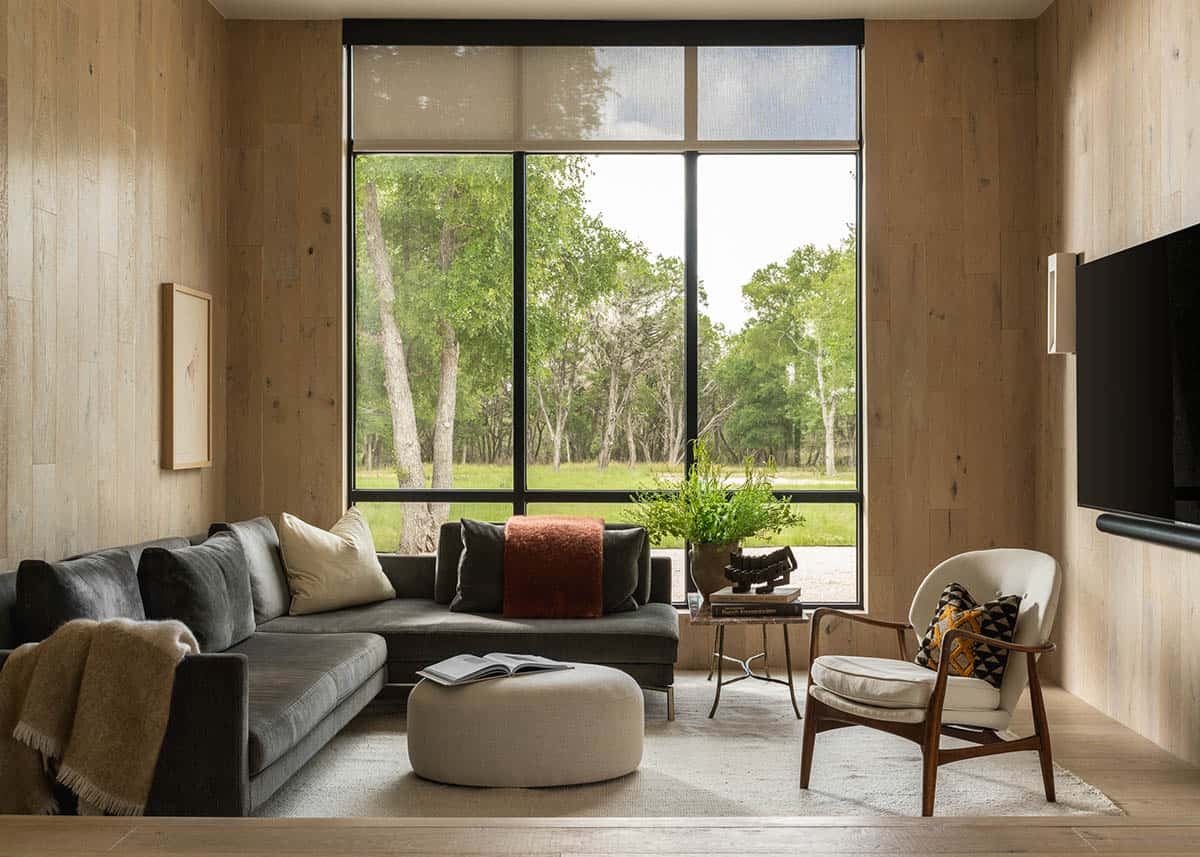 Wood-paneled family room with sectional sofa framed by a wall of windows