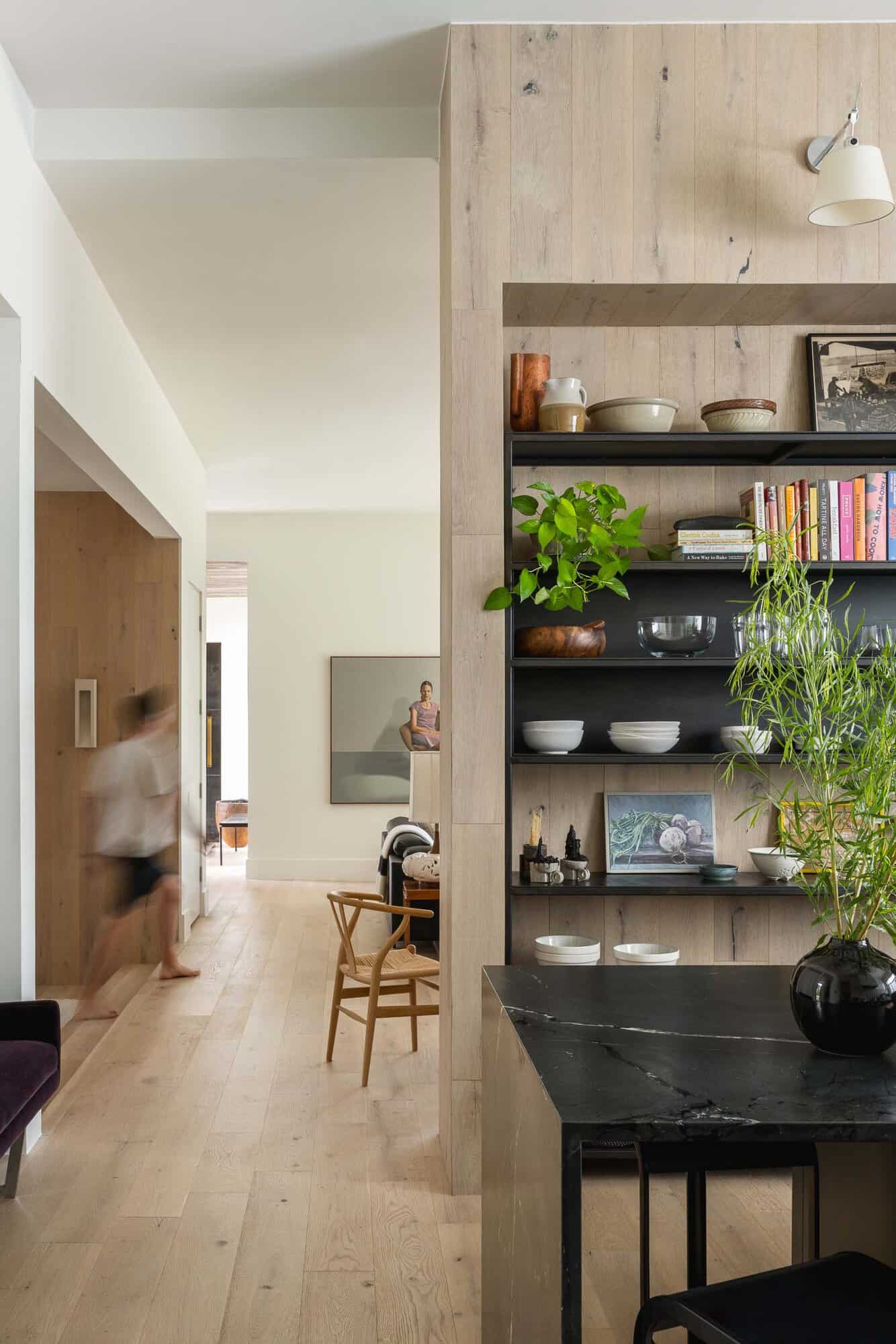 Wood-paneled hallway leads past open shelving toward the dining nook
