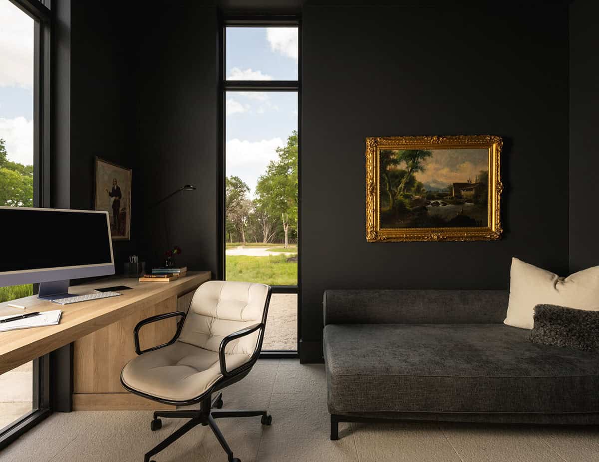 Black-walled home office with built-in oak desk facing floor-to-ceiling windows